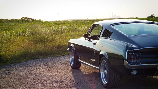 Antons sorte Ford Mustang Fastback fra 1967 på en grusvej i solnedgang